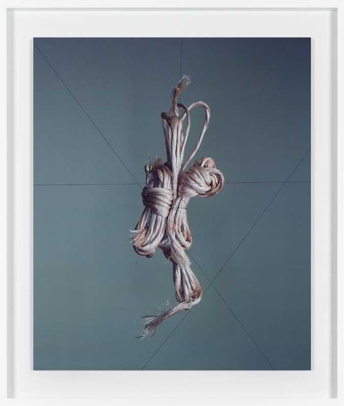 Color image of color photograph depicting suspended twine in white frame