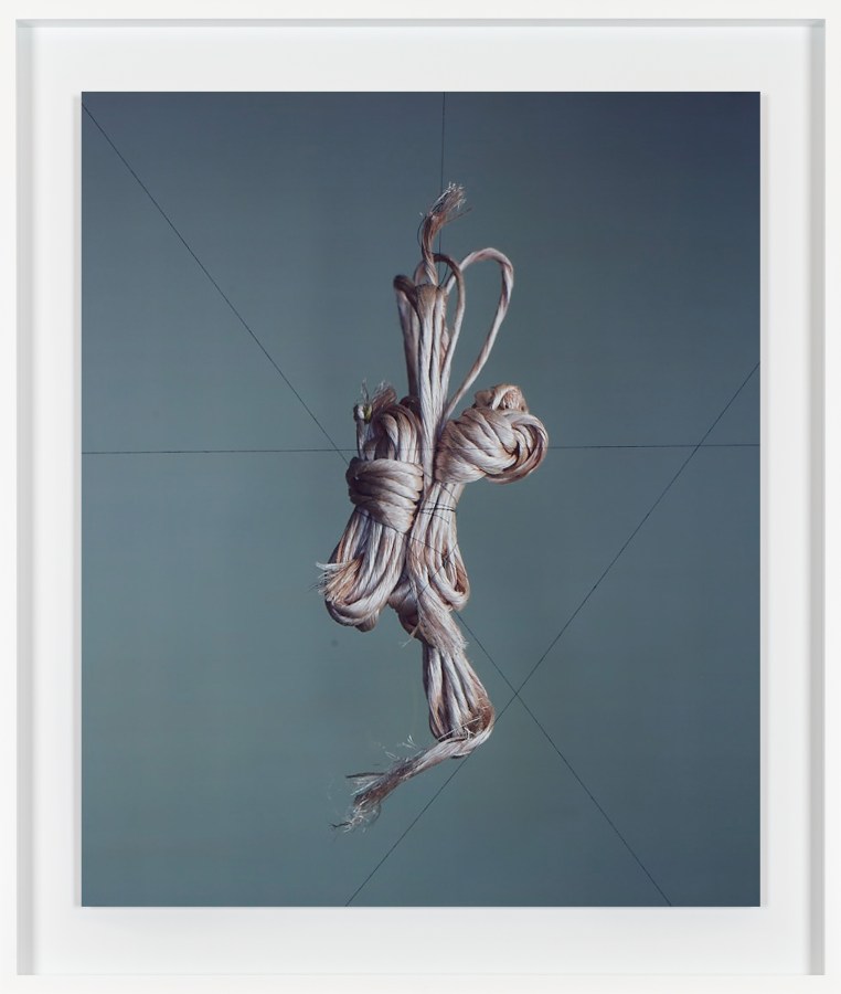 Color image of color photograph depicting suspended twine in white frame