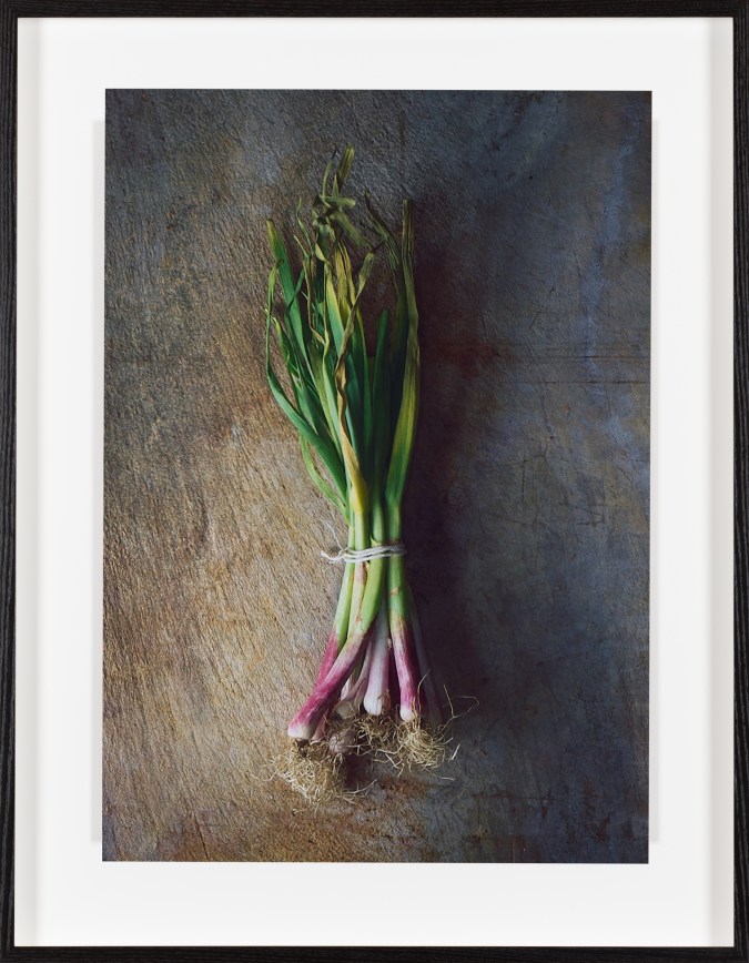 Color photograph of red onions tied together with a white string framed in black
