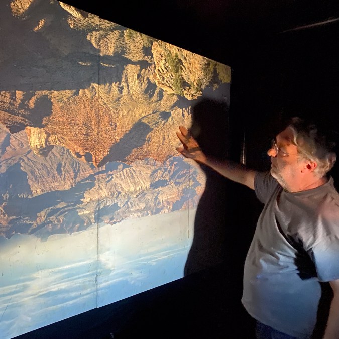 Color image of a figure looking at the inverse of a desert canyon within a large camera obscura