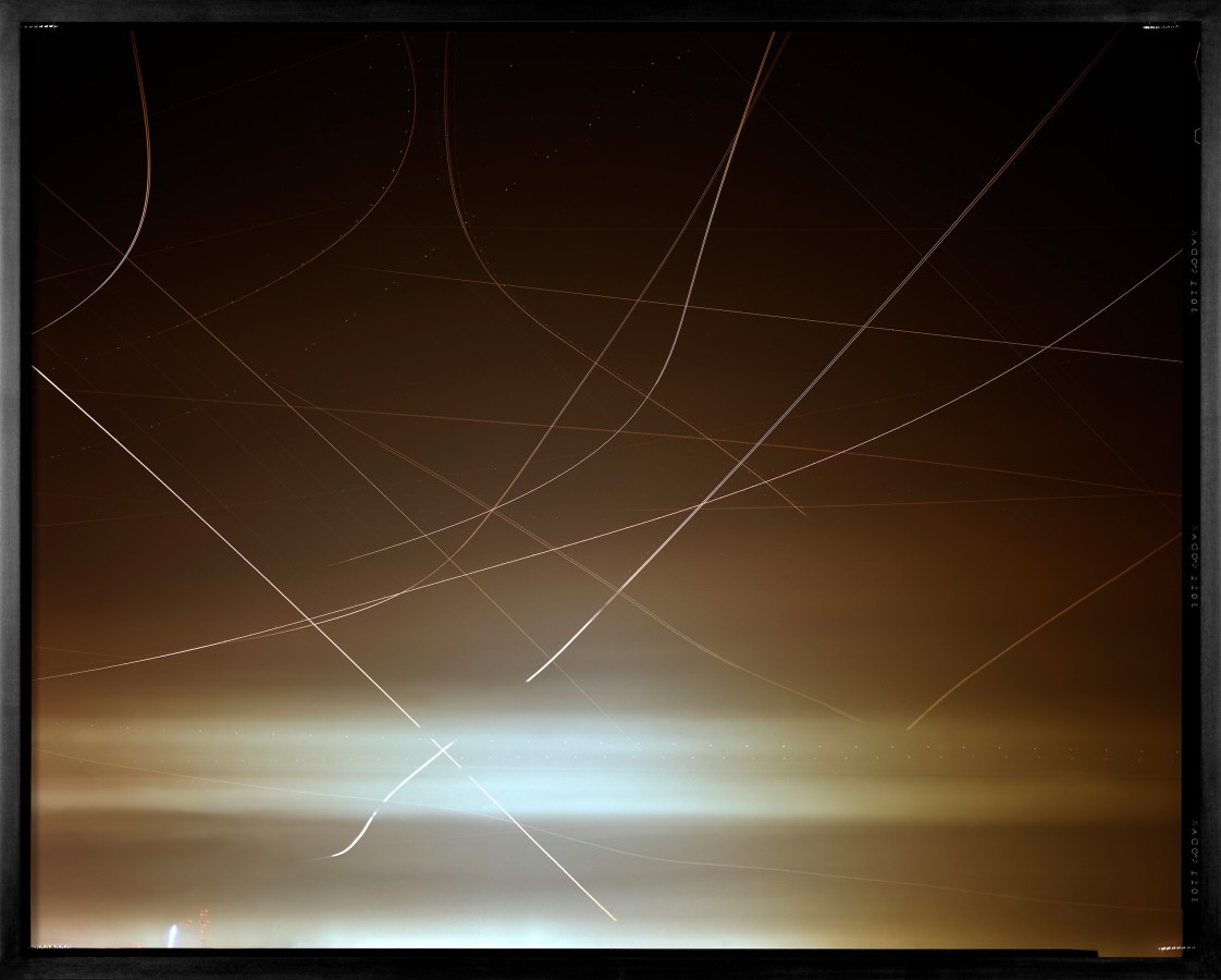 Color image of a color photograph of along exposure depicting air traffic and Venus over san francisco framed in black