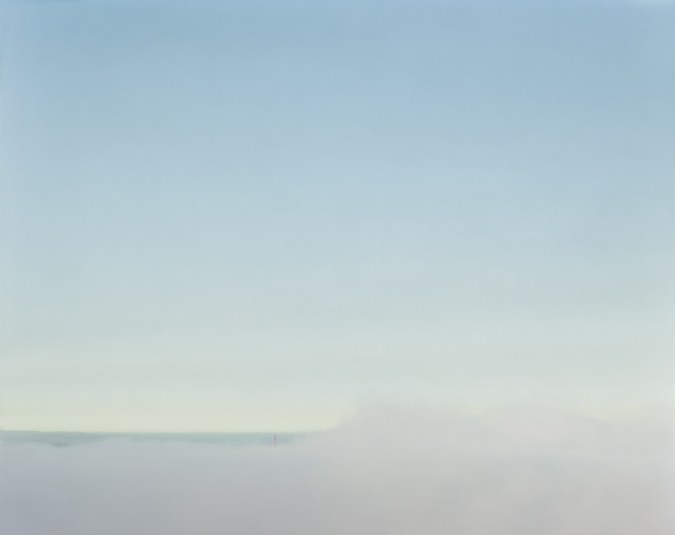 Color photograph of the Golden Gate Bridge on the horizon almost completely obscured by low-lying fog under a clear pale blue sky