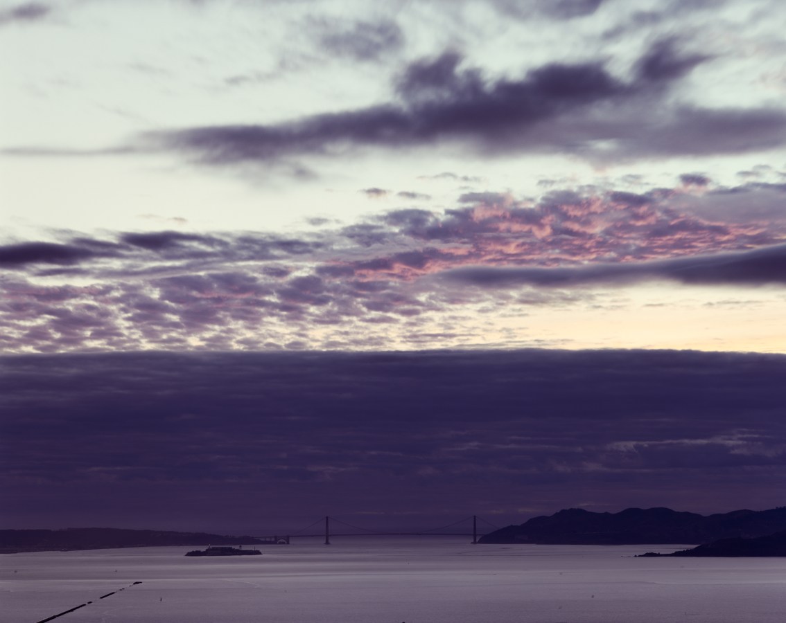 Color image of San Francisco Bay and Golden Gate Bridge under dark blue and pink clouds