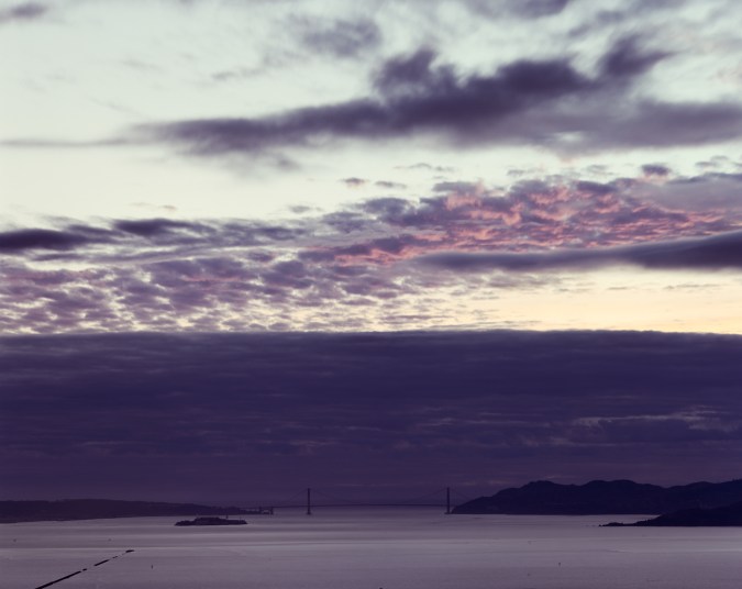 Color image of San Francisco Bay and Golden Gate Bridge under dark blue and pink clouds