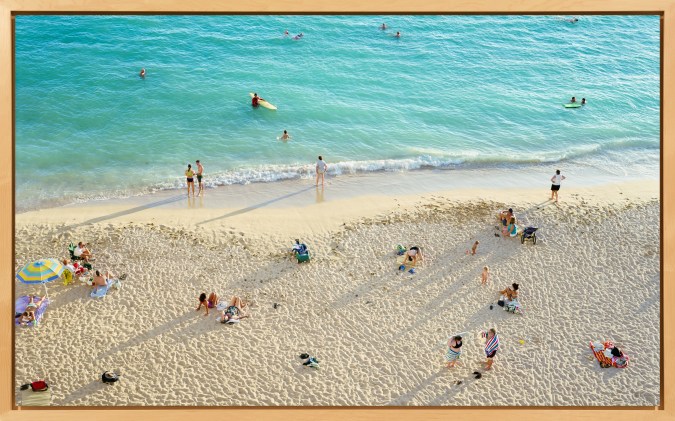 Framed color photograph of the seashore, with people in the water and on the sand