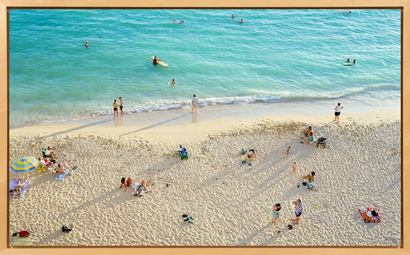 Framed color photograph of the seashore, with people in the water and on the sand