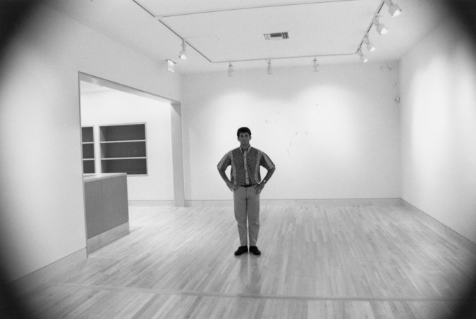 Black and white photograph of a person standing in an empty gallery