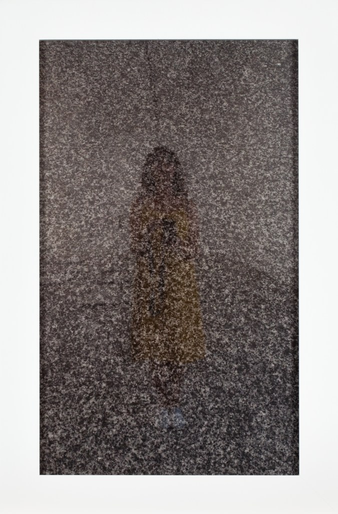 A framed photograph of the photographer's reflection in the surface of a headstone