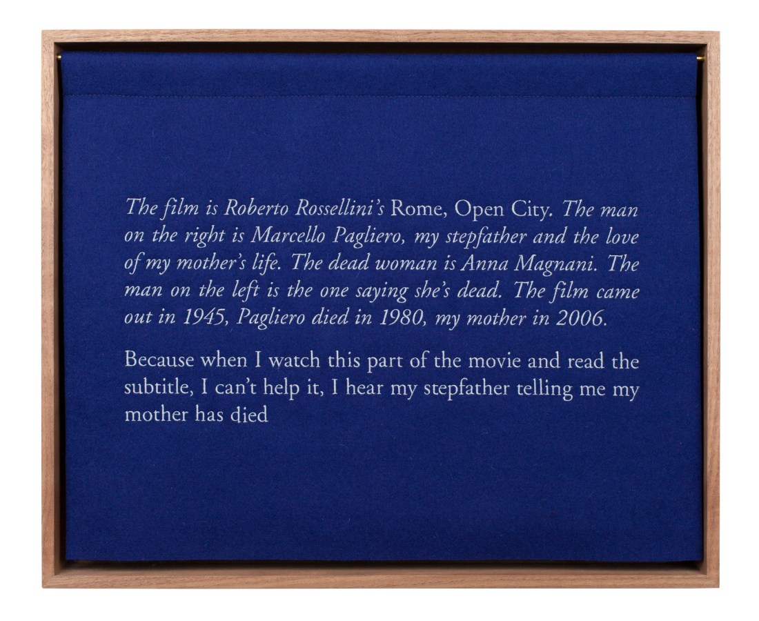 A wooden box with a blue curtian, embroidered with white text, describing the artist's stepfather