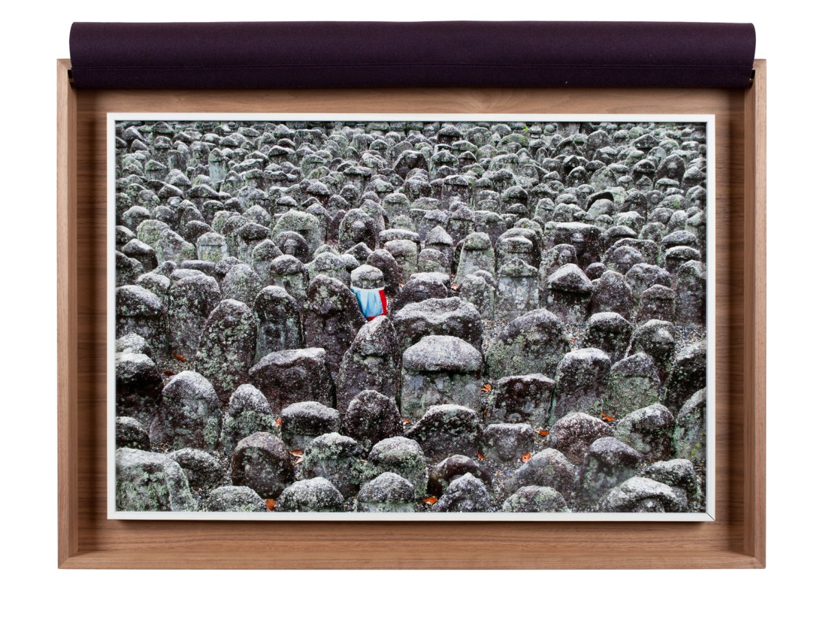 A framed photograph of a graveyard, with an apron around one stone, inside a wooden box