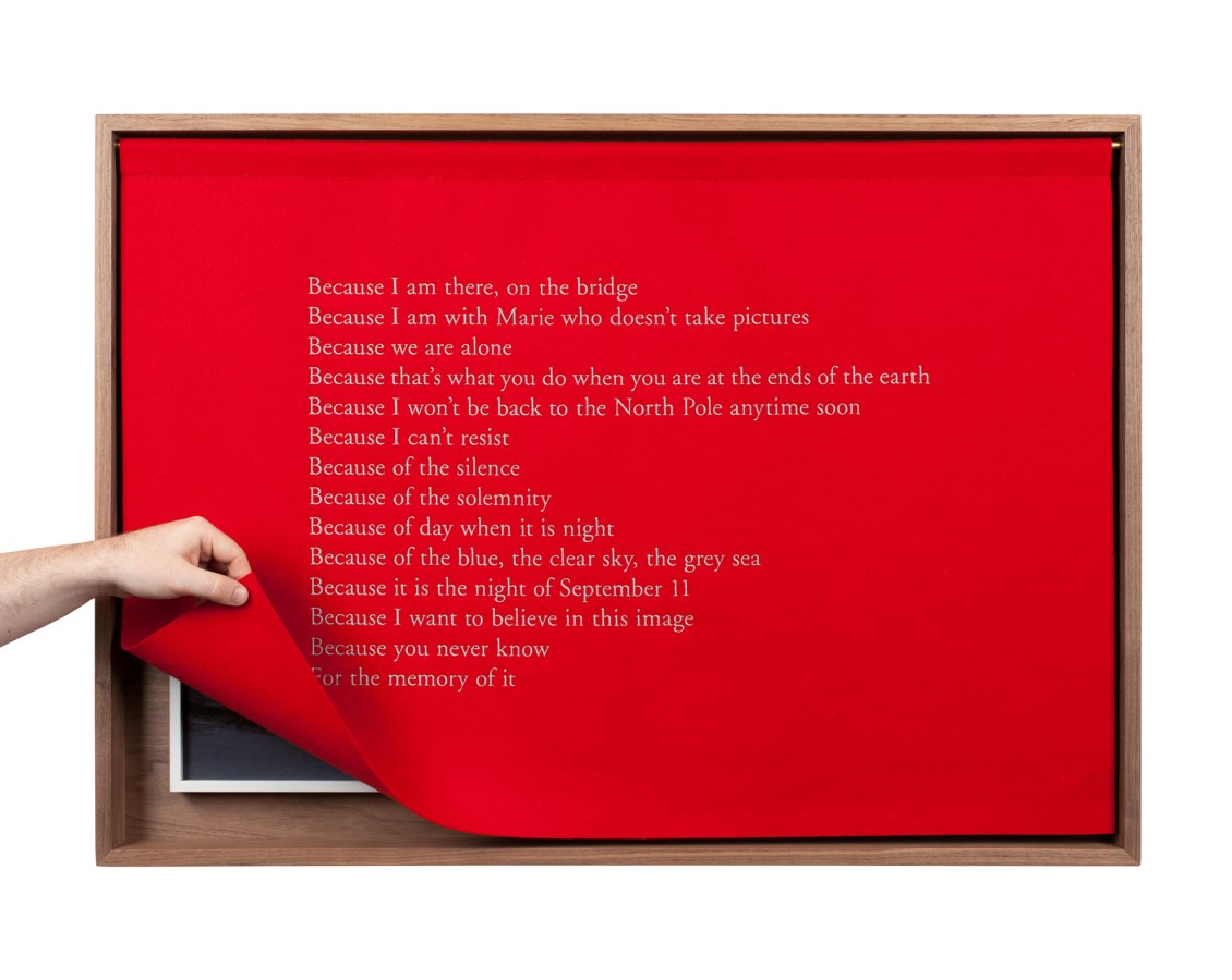 A wooden box with a red felt curtain with white embroidered text, describing the experience of being at the North Pole, the Curtain lifted at the corner by a hand