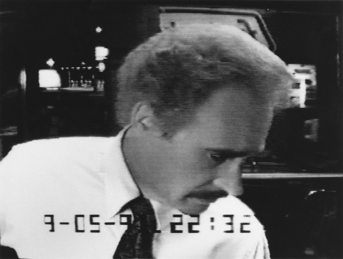 Black and white photograph of mustachioed man at ATM machine