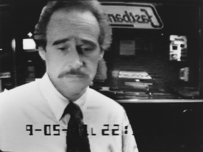 Black and white photograph of mustachioed man at ATM machine
