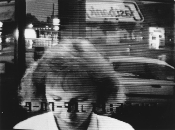 Black and white photograph of a woman at an ATM