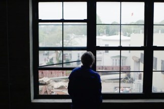 Color still of artist Liz Deschenes looking out her studio windows