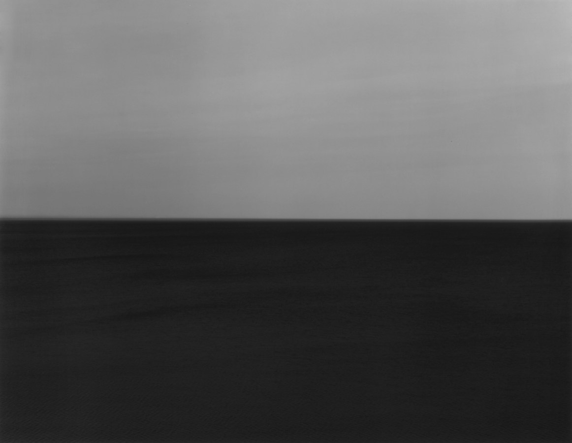 Black-and-white photograph of a seascape with a dark gray sky and very dark water