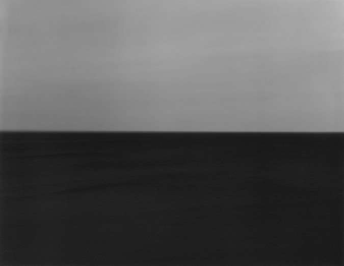 Black-and-white photograph of a seascape with a dark gray sky and very dark water