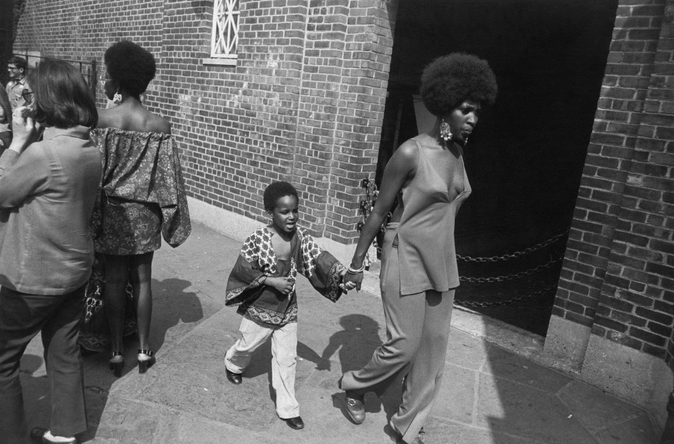 Black and white photograph of a women walking hand in hand with child