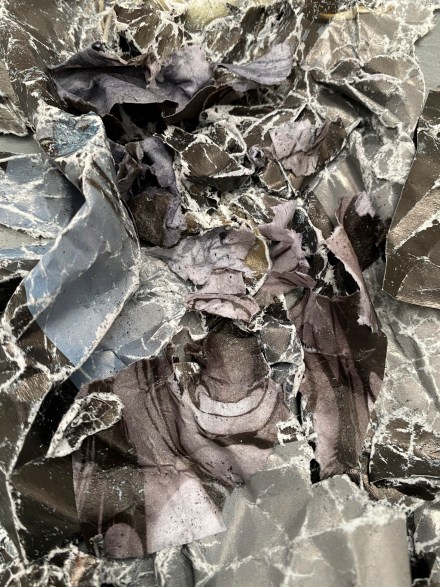 A color photograph of a crumpled illustration from a comic book, with a screaming mouth at the center