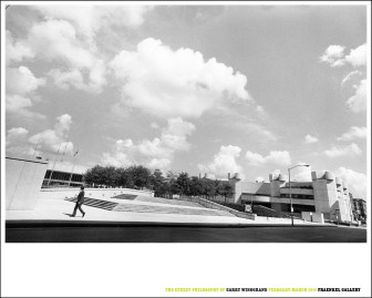 Color image of a poster with a black and white photograph of a figure walking down an empty sidewalk