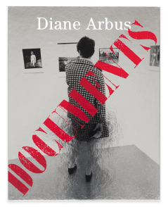 An image of a silver-toned book cover depicting a person looking at art with the word "DOCUMENTS" displayed in red overlaid above