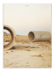 Color image of a book cover depicting several cylindrical concrete sculptures on the desert ground